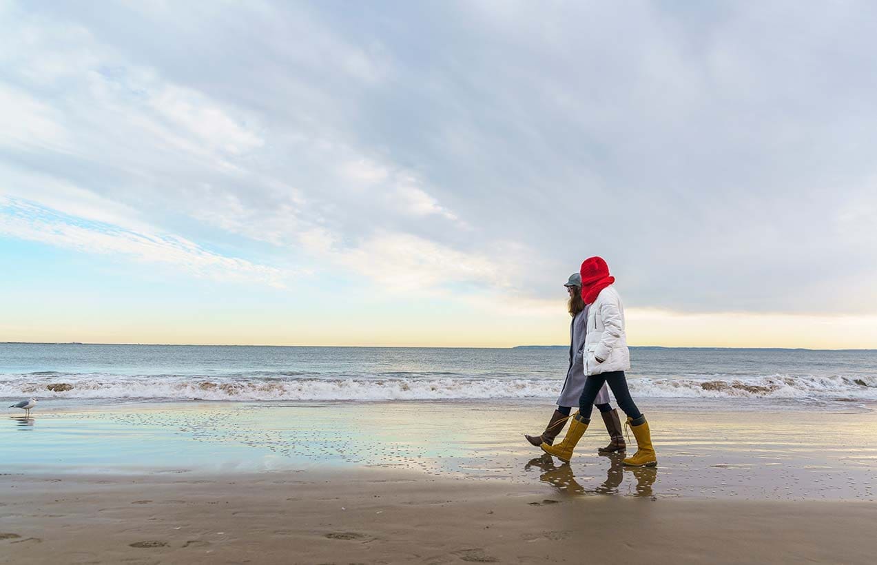Two people walking on the beach at Brighton, UK