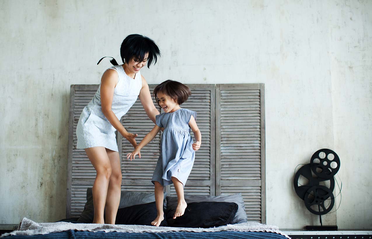 Picture of a mother and her child jumping playfully on a bed.
