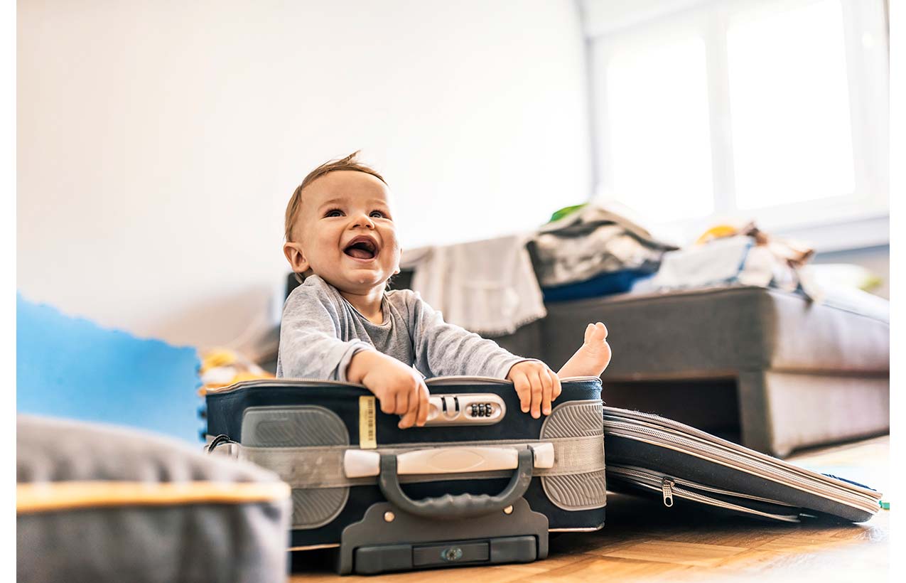 Happy baby boy sitting in a suitcase