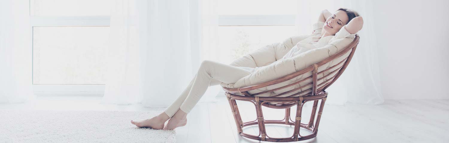 Moving home services - woman relaxing on large wicker chair.