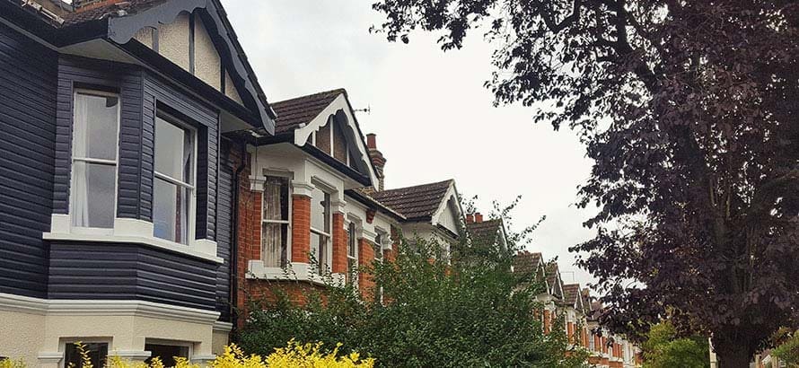 View down a residential road in Ealing London, showing a line of red brick terraced houses.