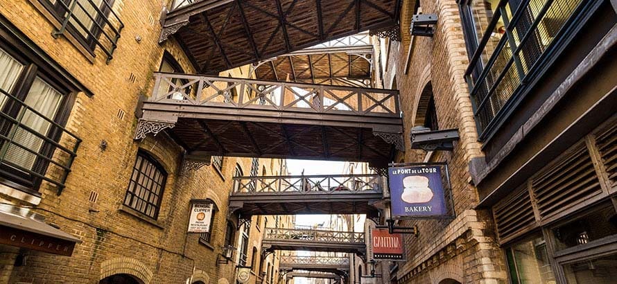 A view down a market street in Bermondsey in London, with shops to both side and bridges between the two sides.