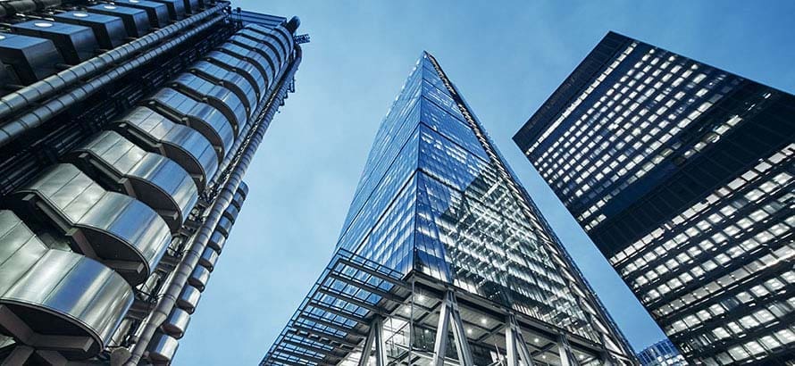View from below, looking up at three modern glass skyscrapers in the city of London's financial district.