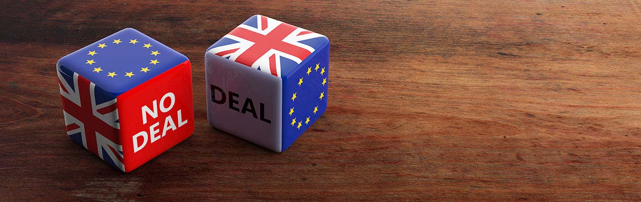 Two dice on a table, one with the european flag and no deal showing on its sides, the other with the UK flag and deal on its sides.
